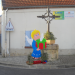 décoration de Noël devant la mairie. on aperçoit un enfant avec des ailes d'anges blond portant un cadeau rouge et vert